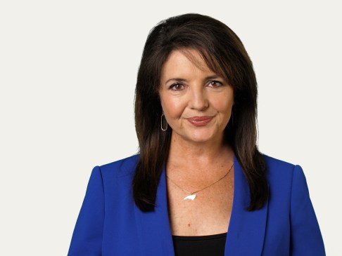 Woman in blue and black top standing against a white background