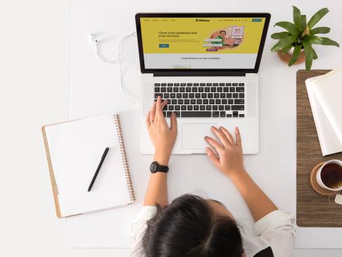 overhead shot of a woman using a laptop at a white desk