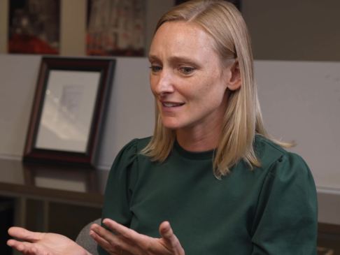 woman in green shirt being interviewed in an office setting