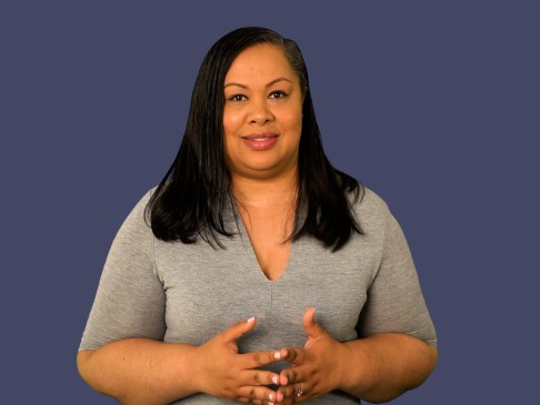 Woman in gray top standing against blue background