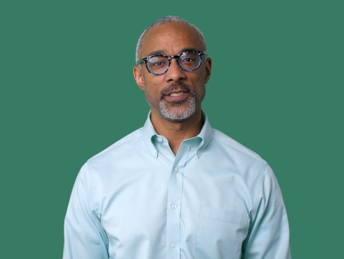 man in glasses and blue shirt against a green background